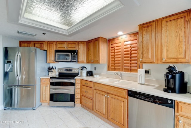 kitchen with a sink, an ornate ceiling, appliances with stainless steel finishes, light countertops, and a raised ceiling