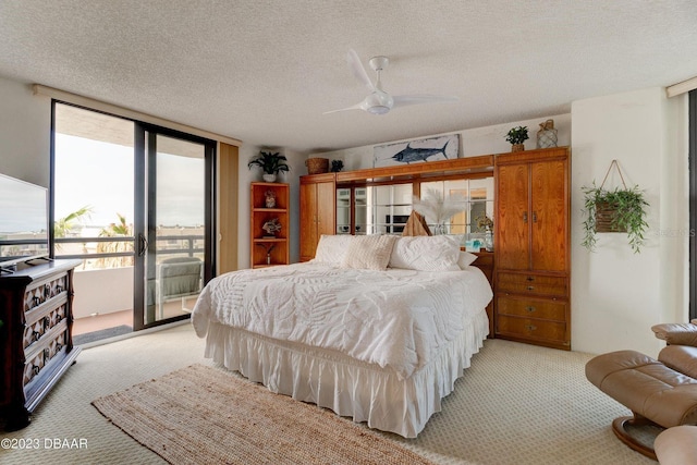 bedroom with light colored carpet, a textured ceiling, and access to outside