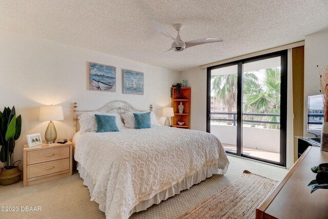 bedroom featuring a wall of windows, a ceiling fan, access to exterior, a textured ceiling, and light colored carpet