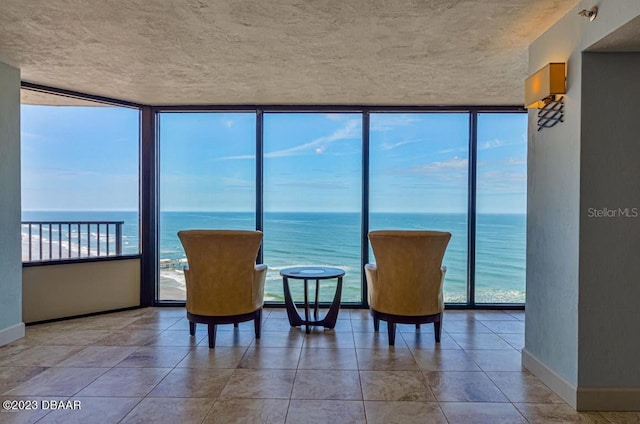 living area with a wealth of natural light, baseboards, a water view, and floor to ceiling windows