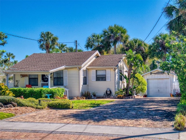 single story home with decorative driveway, a garage, a porch, and an outdoor structure