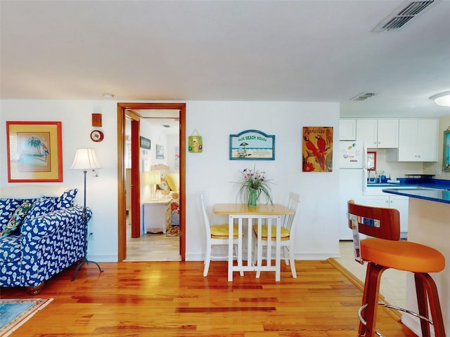 dining area with light wood finished floors, visible vents, and baseboards