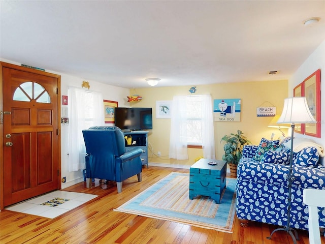 living room featuring hardwood / wood-style flooring, plenty of natural light, visible vents, and baseboards