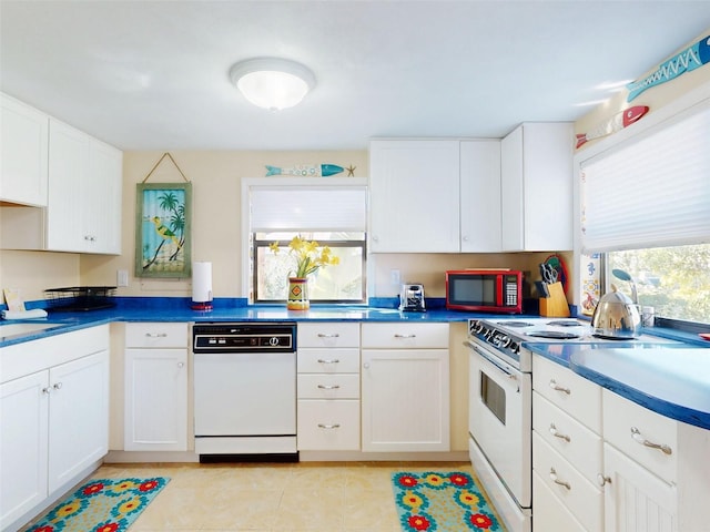 kitchen featuring white cabinetry, white appliances, light tile patterned flooring, and dark countertops