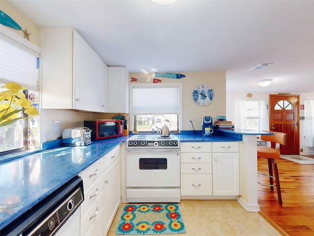 kitchen with visible vents, white appliances, a breakfast bar area, and white cabinets