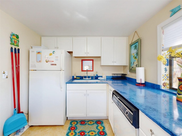 kitchen with white appliances, dark stone countertops, light tile patterned flooring, a sink, and white cabinetry