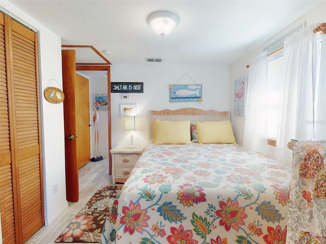 bedroom featuring light wood-style floors, visible vents, and a closet