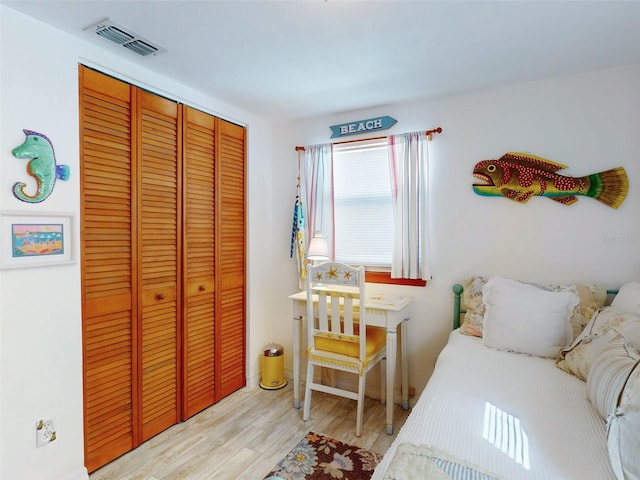 bedroom with a closet, visible vents, and light wood-type flooring