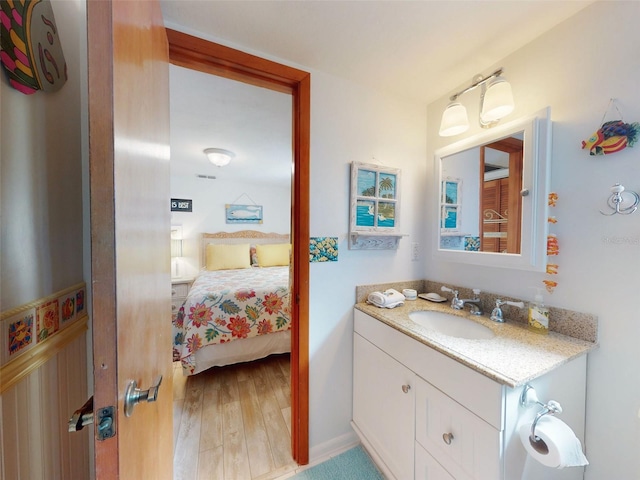 ensuite bathroom featuring ensuite bath, vanity, and wood finished floors