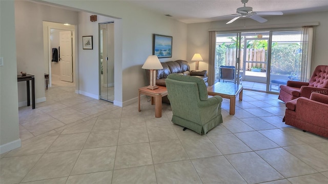 living area featuring light tile patterned floors, baseboards, and ceiling fan