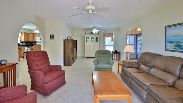 living room with light tile patterned floors, arched walkways, and a ceiling fan