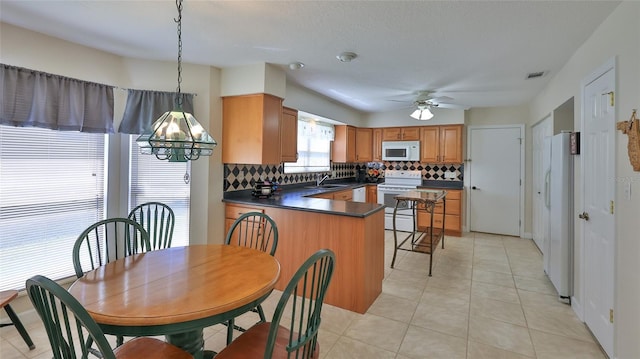 kitchen with dark countertops, visible vents, ceiling fan with notable chandelier, white appliances, and a sink