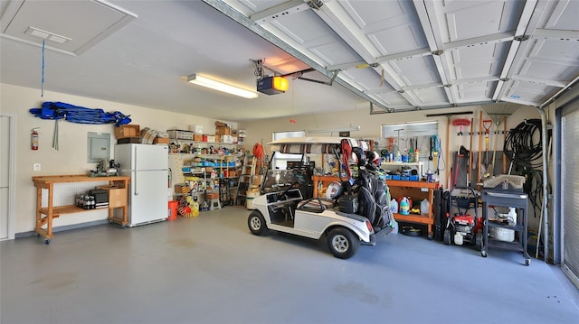 garage featuring a workshop area, a garage door opener, and freestanding refrigerator