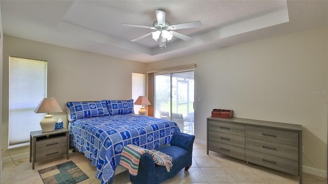 bedroom featuring a raised ceiling, light tile patterned floors, access to exterior, and baseboards