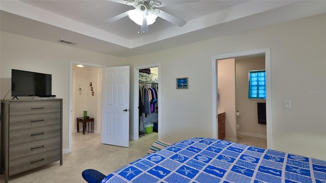 bedroom with light tile patterned flooring, visible vents, ensuite bath, and a raised ceiling