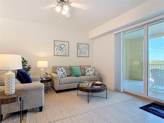 living room with wood finished floors, a ceiling fan, and baseboards