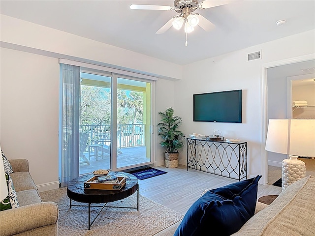 living area with visible vents, baseboards, a ceiling fan, and wood finished floors