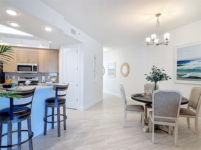 dining room featuring a chandelier, visible vents, light wood finished floors, and baseboards