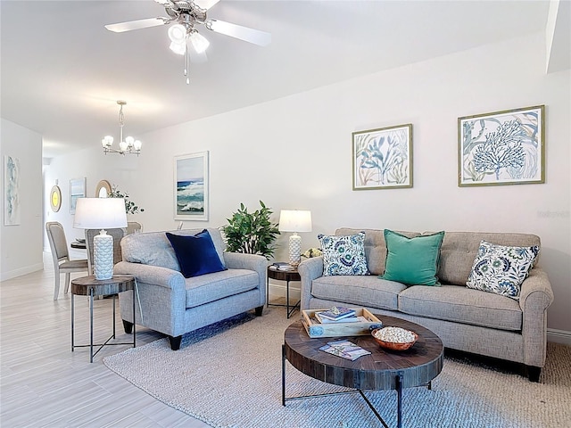 living area with light wood finished floors, baseboards, and ceiling fan with notable chandelier