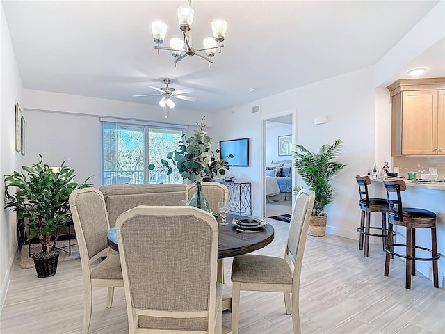 dining area with visible vents, ceiling fan with notable chandelier, and baseboards