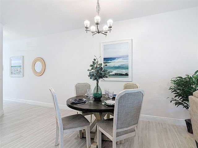 dining space with baseboards, light wood-type flooring, and an inviting chandelier