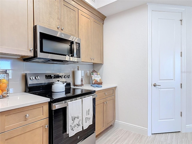 kitchen with stainless steel appliances, baseboards, light brown cabinets, and light countertops