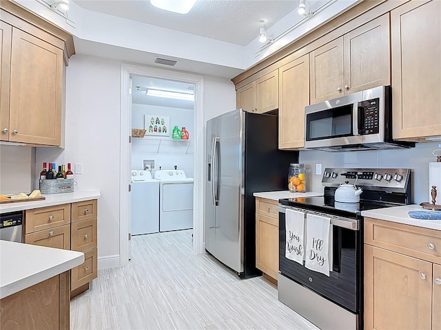 kitchen with separate washer and dryer, appliances with stainless steel finishes, and light countertops