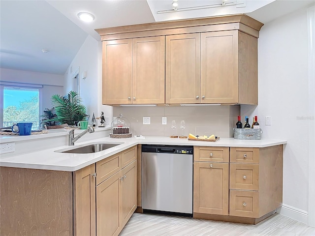 kitchen featuring a sink, stainless steel dishwasher, a peninsula, and light countertops