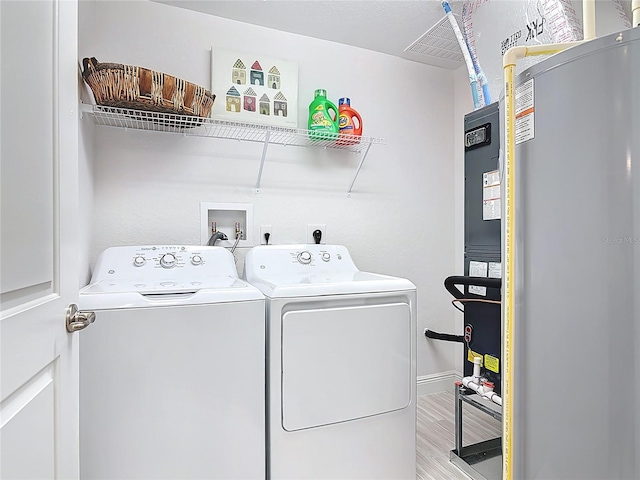 laundry area featuring wood finished floors, baseboards, laundry area, water heater, and independent washer and dryer