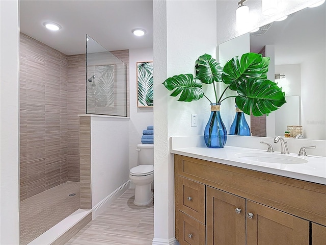 bathroom with visible vents, toilet, a walk in shower, baseboards, and vanity