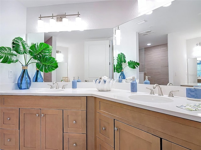 full bathroom with a sink, visible vents, double vanity, and a tile shower