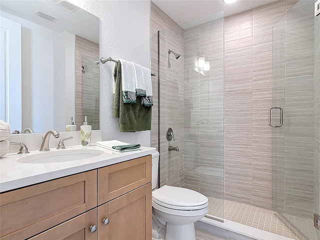 full bathroom featuring vanity, toilet, visible vents, and a stall shower