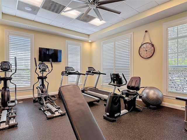 gym featuring a paneled ceiling, baseboards, and a wealth of natural light