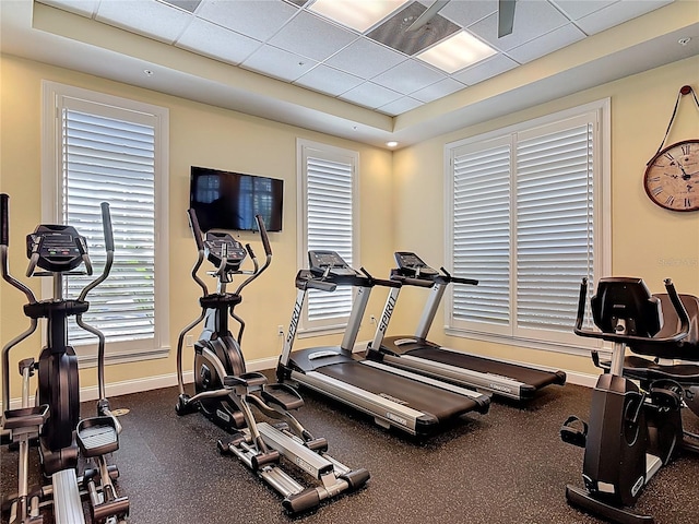 workout area featuring a paneled ceiling and baseboards