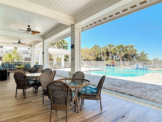 view of patio / terrace featuring outdoor dining area, a community pool, ceiling fan, and fence