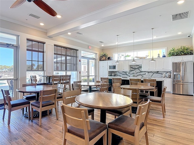 dining area featuring visible vents, light wood-type flooring, ceiling fan, and ornamental molding