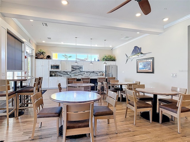 dining space with ceiling fan, visible vents, light wood-type flooring, and ornamental molding