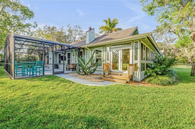 550 Bottlebrush Ct, New Smyrna Beach, FL 32168 - back of property with a yard, glass enclosure, a chimney, and a shingled roof