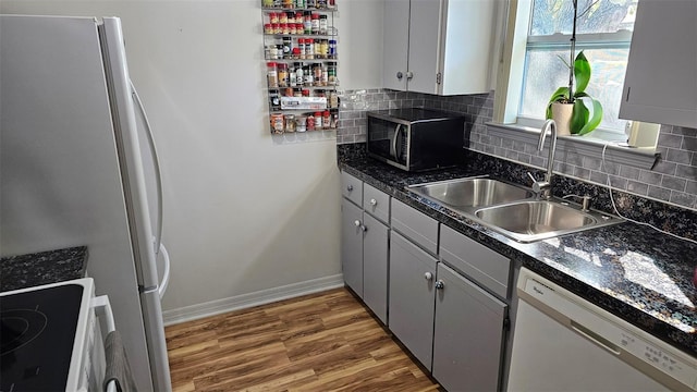 919 Fairvilla Dr, New Smyrna Beach, FL 32168 - kitchen with dark countertops, tasteful backsplash, light wood-style floors, white appliances, and a sink