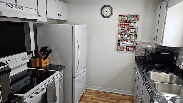919 Fairvilla Dr, New Smyrna Beach, FL 32168 - kitchen with backsplash, under cabinet range hood, light wood-style floors, white electric stove, and a sink