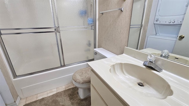 919 Fairvilla Dr, New Smyrna Beach, FL 32168 - full bath with vanity, bath / shower combo with glass door, tile patterned floors, stacked washer / dryer, and toilet