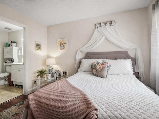 168 Turnberry Cir, New Smyrna Beach, FL 32168 - bedroom featuring visible vents, a textured ceiling, connected bathroom, and hardwood / wood-style flooring