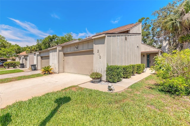 210 Pine Cone Trl, Ormond Beach, FL 32174 - view of side of home with a garage, driveway, board and batten siding, and a yard
