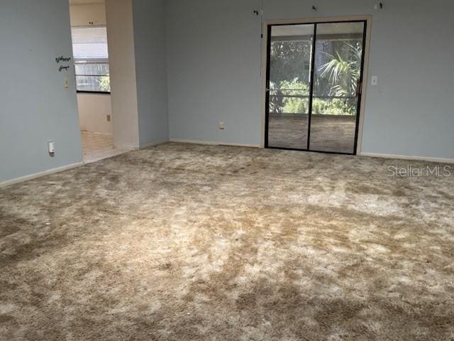 carpeted empty room featuring baseboards