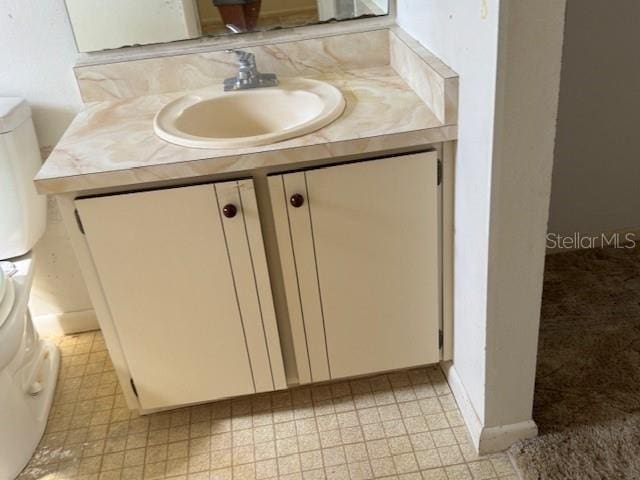 bathroom with toilet, vanity, and tile patterned floors