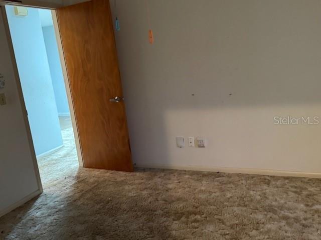 empty room featuring baseboards and carpet