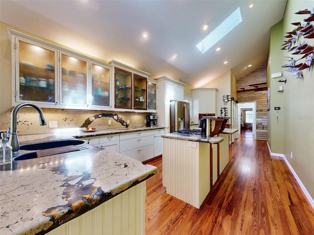 536 Faulkner St, New Smyrna Beach, FL 32168 - kitchen featuring high vaulted ceiling, a skylight, a sink, light wood-style floors, and stainless steel fridge with ice dispenser