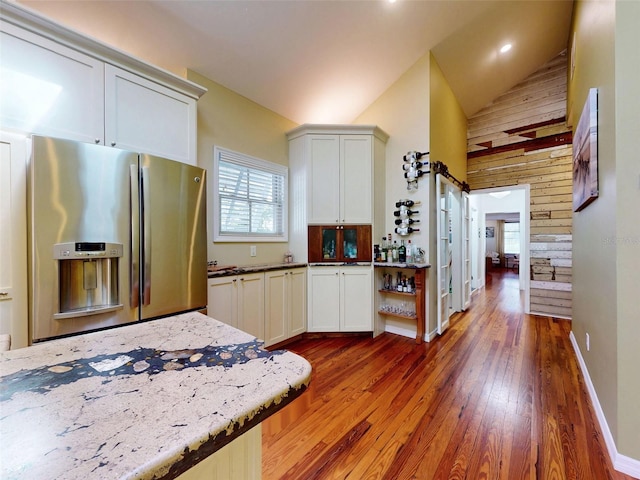 536 Faulkner St, New Smyrna Beach, FL 32168 - kitchen with high vaulted ceiling, hardwood / wood-style floors, light stone countertops, white cabinetry, and stainless steel fridge with ice dispenser