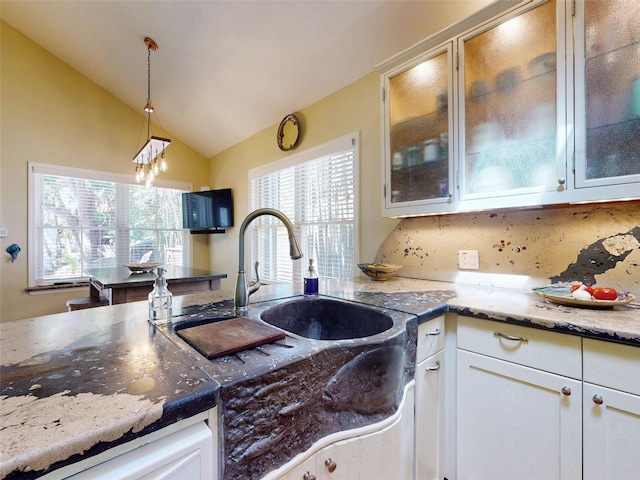 536 Faulkner St, New Smyrna Beach, FL 32168 - kitchen featuring vaulted ceiling, light stone countertops, hanging light fixtures, glass insert cabinets, and decorative backsplash