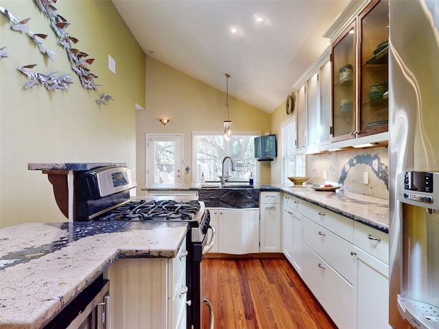 536 Faulkner St, New Smyrna Beach, FL 32168 - kitchen with wood finished floors, a peninsula, lofted ceiling, stainless steel appliances, and white cabinets